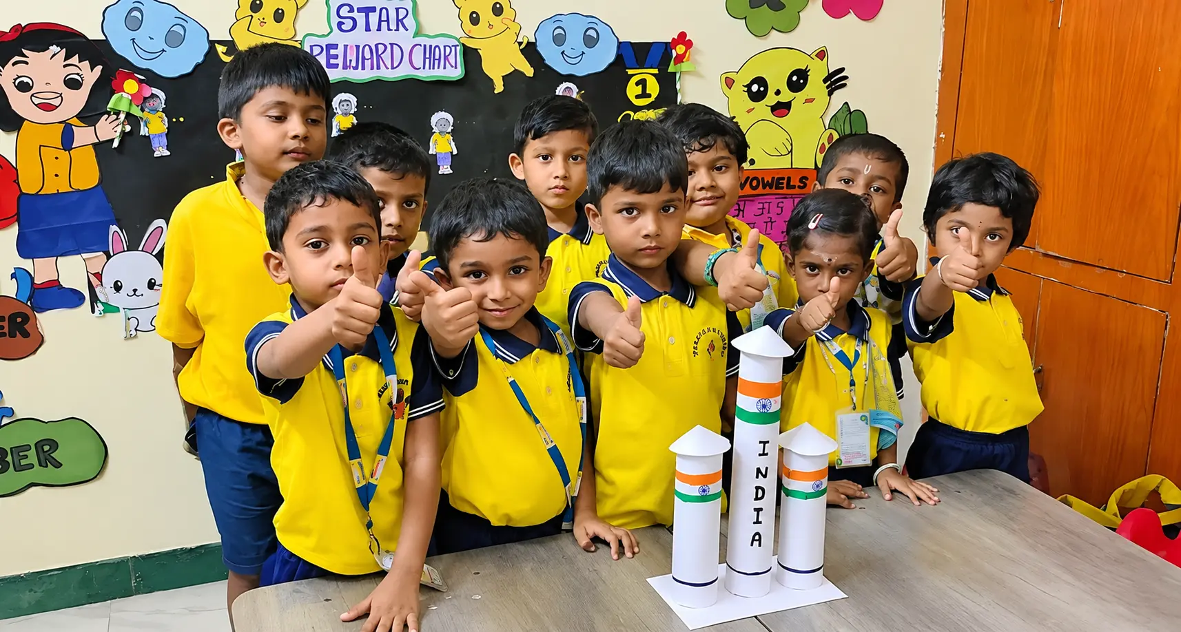 Preschool children in yellow uniforms giving a thumbs up